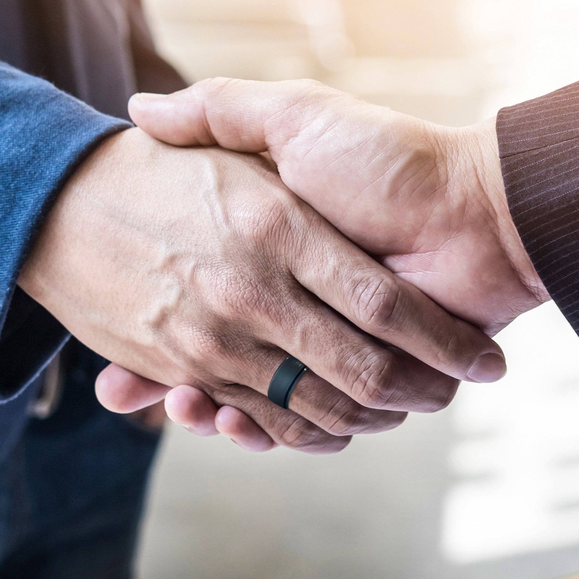 Professional handshake with silicone rings visible on finger