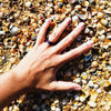 Woman’s hand wearing silicone ring on the beach with seashells