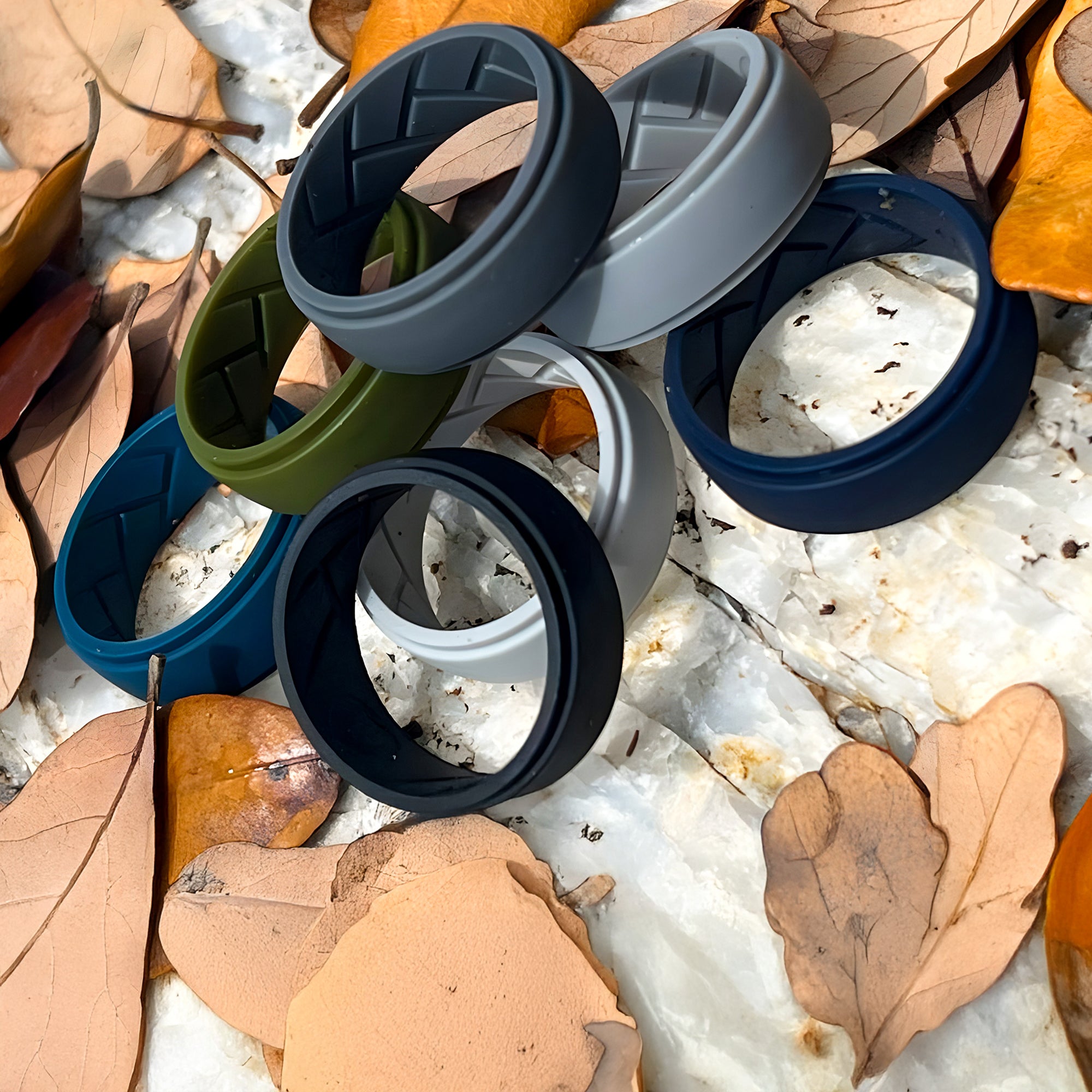 Colorful silicone rings displayed on natural stone and autumn leaves – eco-inspired, durable and hypoallergenic accessories